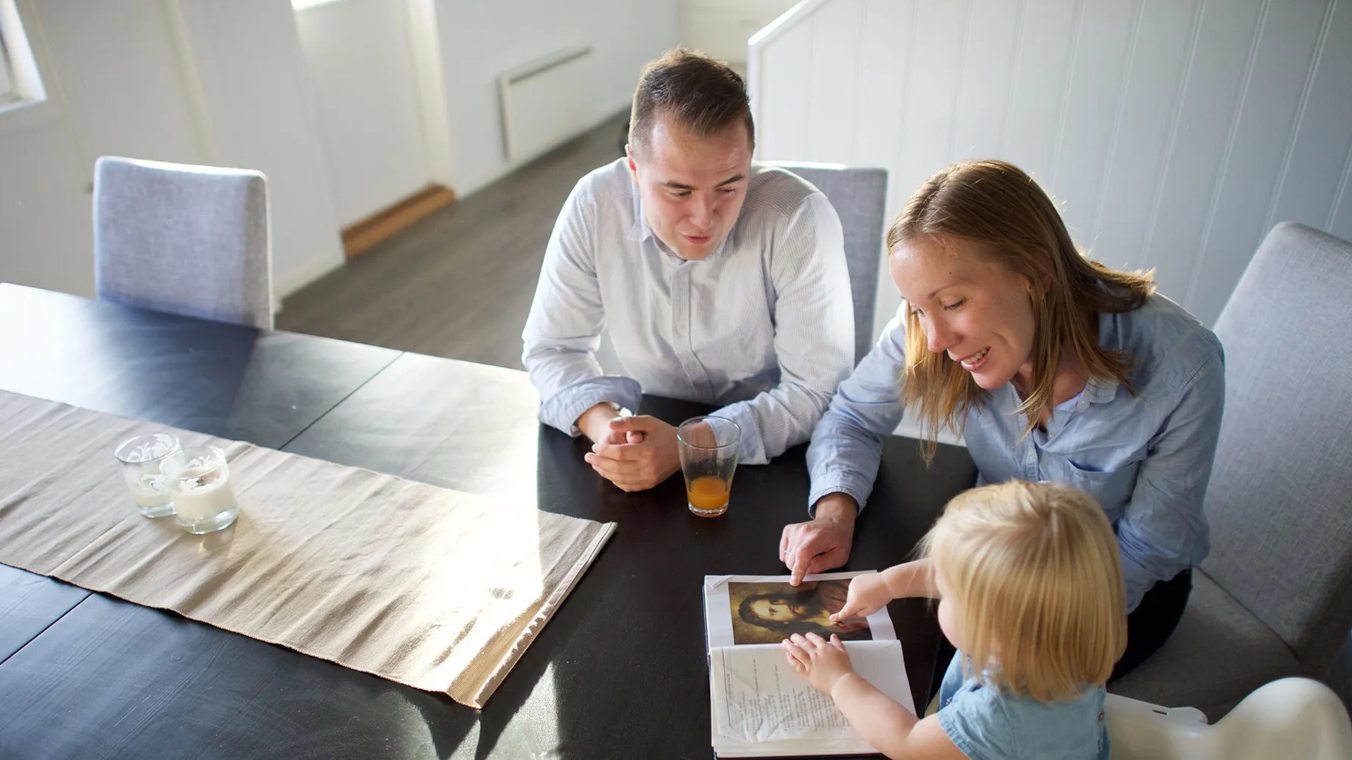 A family reads scriptures around a table.